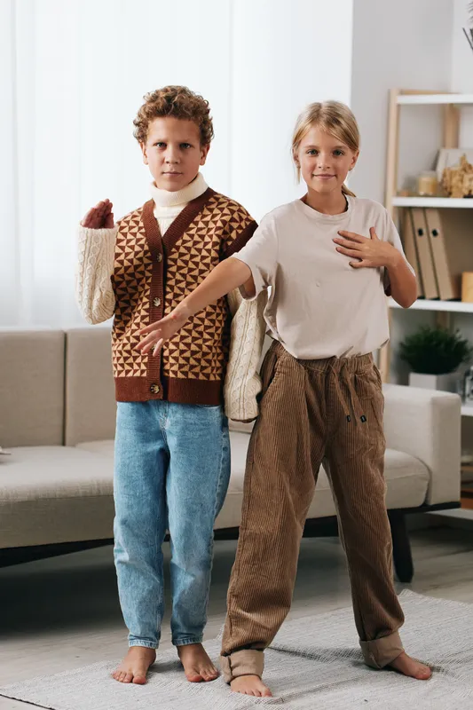 Authentic playful scene with two children at home, dressed in casual school style, posing confidently as if in a friendly class, capturing movement and youth.