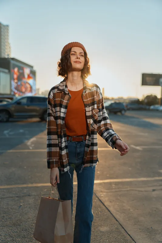 Woman shopping in urban city street at golden hour glow, candid authenticity and lifestyle moment. Emotional storytelling portrait of mindful living, casual fashion and confidence.