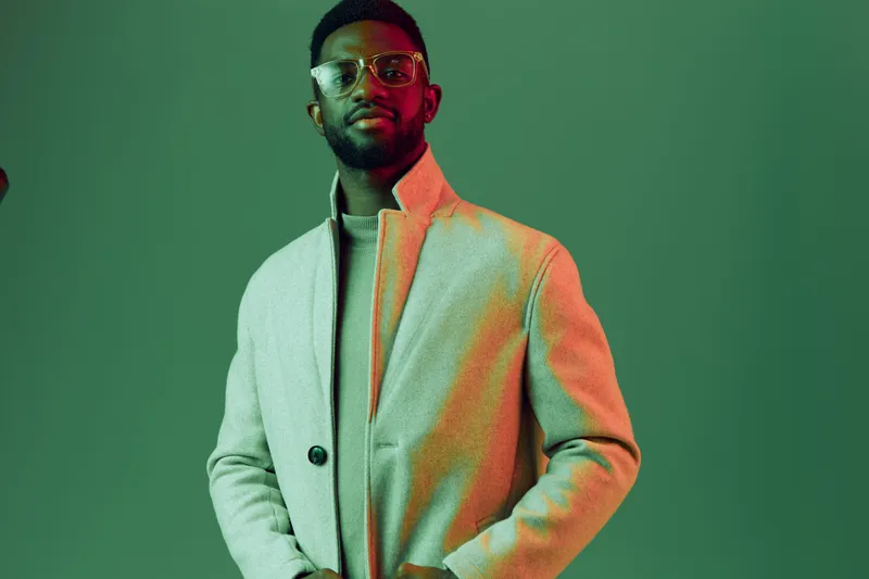 Stylish man in a gray coat against a green background, exuding confidence and elegance, perfect for fashion concepts and seasonal trends