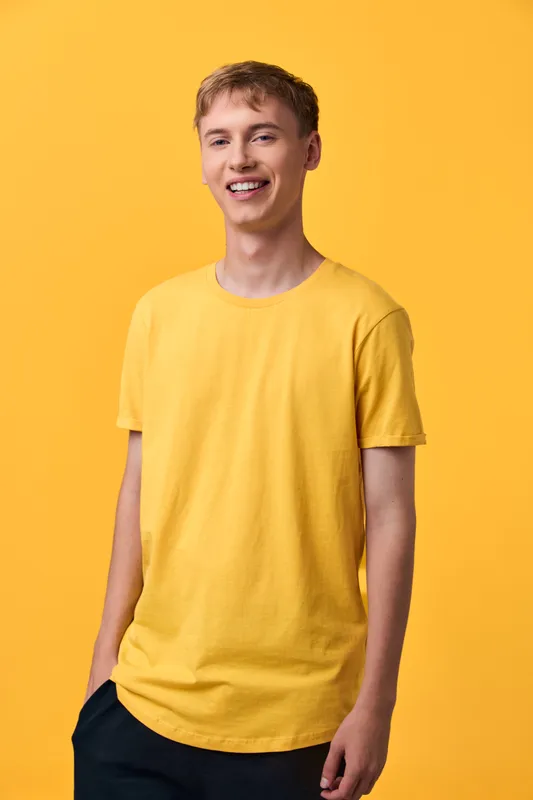 Smiling man in a yellow t shirt stands against a matching yellow backdrop, casual fashion, relaxed pose, studio shot, vibrant color harmony and confident mood