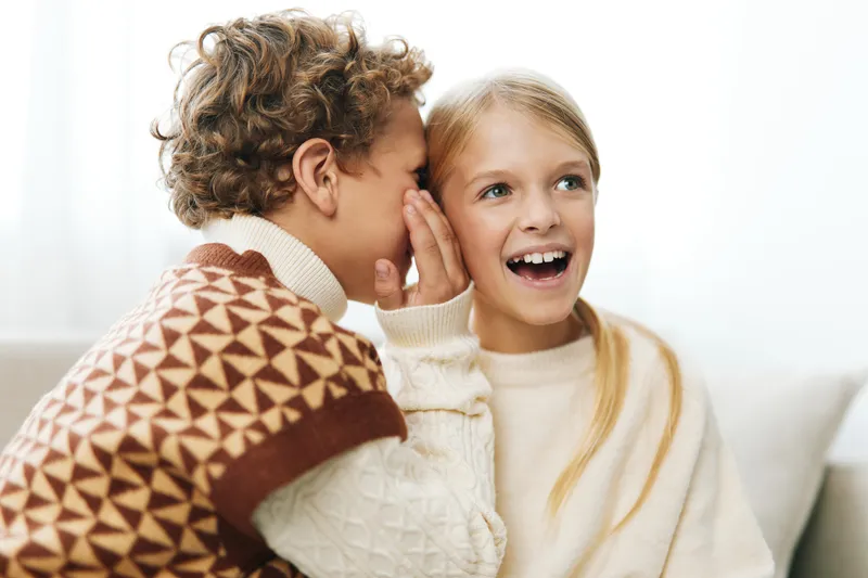 Authentic moment of playful interaction between siblings in a cozy home, capturing a lighthearted scene that hints at school life, learning, and simple games that enrich daily routine.