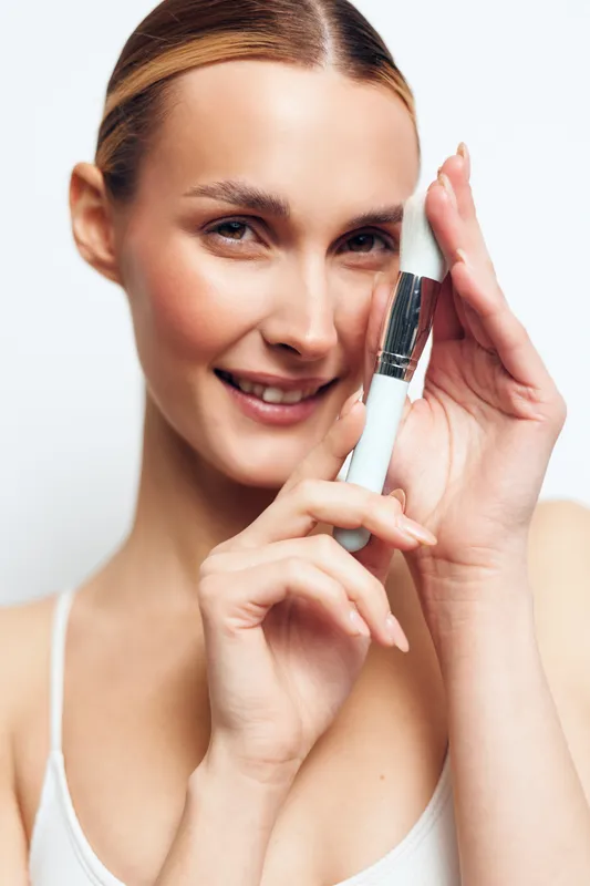 Woman applying serum on face in close up portrait, smiling and confident, focusing on smooth skin and beauty care routine, self care concept for wellness and skincare