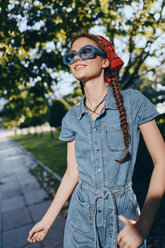 lifestyle woman in modern boho-western denim street style wearing sunglasses and red bandana, captured with warm film color aesthetic in urban outdoor setting