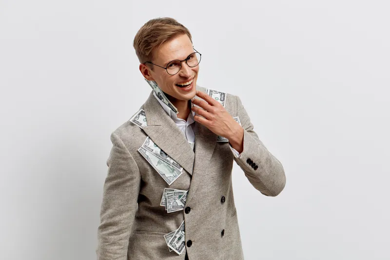 Smiling young man wearing beige coat with money inside cash financial success concept studio portrait