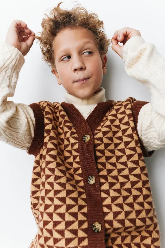 An authentic moment of childhood captures a child in a cozy knitted vest, highlighting a playful school vibe and a genuine lifestyle that celebrates curiosity.