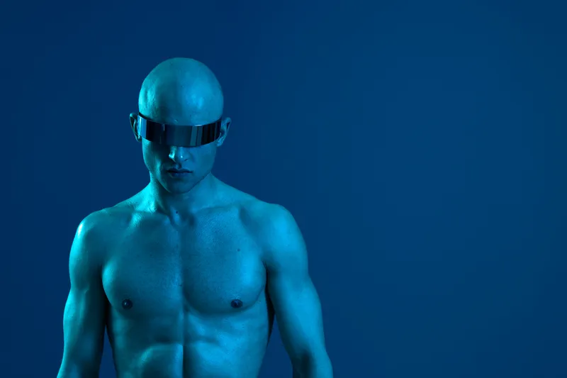 Young man posing confidently in a futuristic blue tone, wearing stylish sunglasses. This modern and striking image showcases bold fashion and futuristic aesthetics.