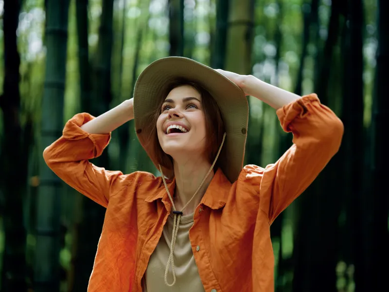 woman hat smile bamboo nature forest happy portrait of young woman in wide brim hat laughing and looking up amid tall bamboo grove, outdoor travel scene with green foliage and relaxed mood
