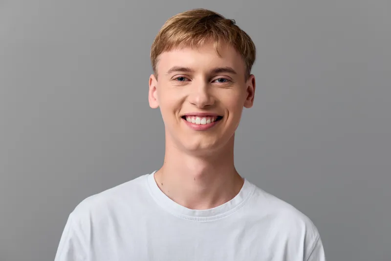 Smiling man in casual white shirt against a simple studio backdrop headshot style, friendly approachable expression, suitable for lifestyle or corporate use