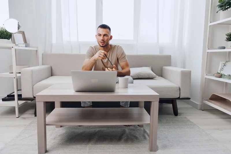 Engaging man working remotely in a bright, modern home office, providing a fresh perspective on remote work and productivity in 2025 trends.