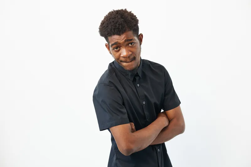Confident African American man wearing a black shirt, showcasing a thoughtful expression against a clean, white background. Perfect for professional contexts.
