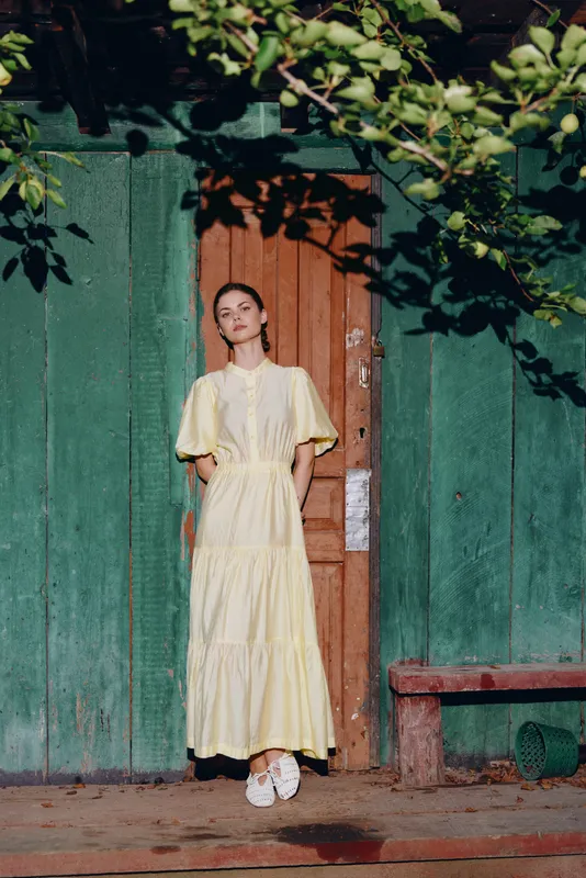 Woman yellow dress wooden door green wall sunlight, authentic inclusive
