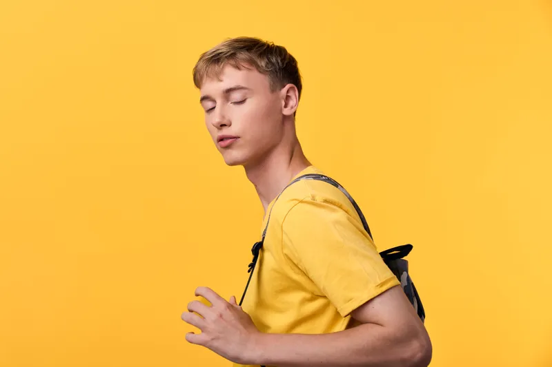 Backpack, yellow, male, casual, lifestyle, streetwear in a bright studio scene, a relaxed pose with a yellow shirt and simple backdrop, clean composition and modern youth vibe