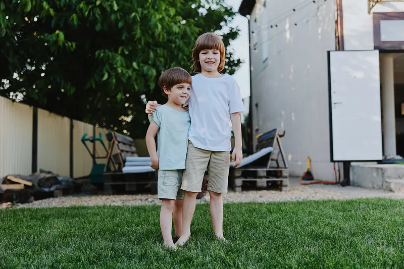 Happy children playing outside in a sunny backyard, enjoying a carefree moment together. Their joyful expressions capture the essence of childhood friendships and laughter.