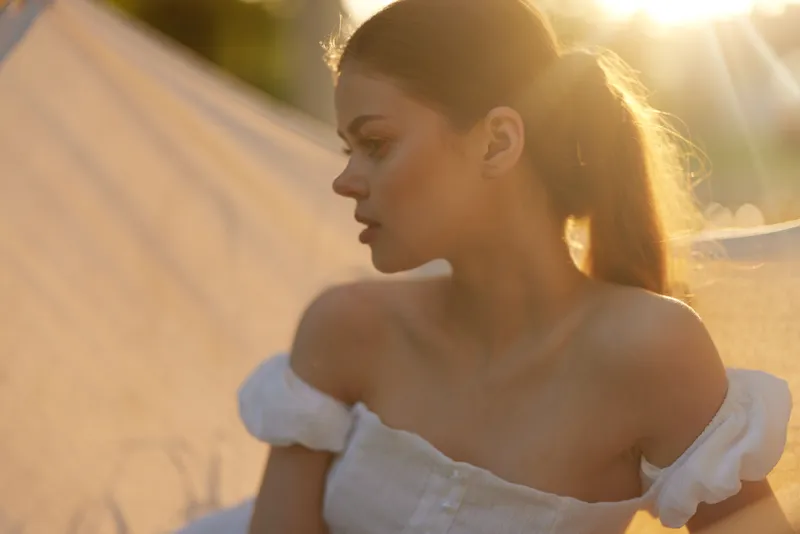 Young model in summer dress, soft sunlight illuminating her profile, evokes emotions of tranquility and beauty in nature Seasonal, warm color palette enhances the concept