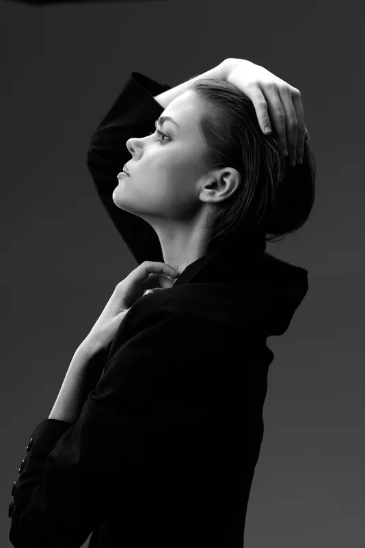 Black and white portrait of a thoughtful woman with slicked-back hair wearing a dark jacket.