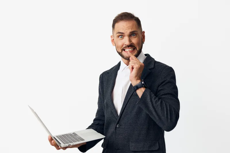 A confident business professional man on an isolated colored background, expressing thoughtful emotion while using a laptop, conveying focus, strategy, and clear communication.