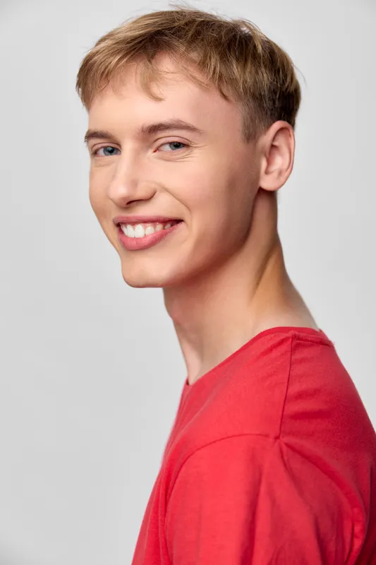 Smiling male headshot in a red shirt, studio lighting, casual confident mood, clean background, suitable for lifestyle, marketing, or branding projects.