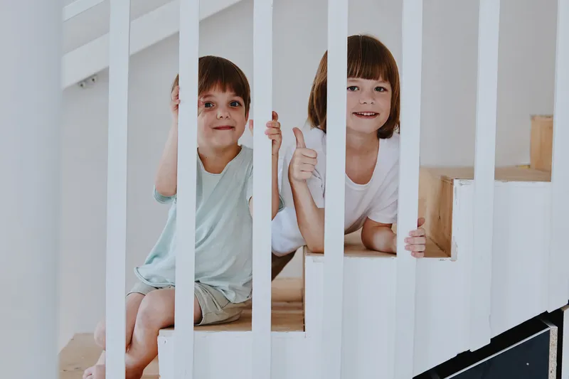 Happy children playing on the stairs, showing joy and excitement in a bright, modern interior, perfect for family-oriented themes and childhood memories.