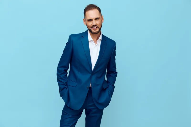 Professional businessman stands confidently in a tailored blue suit against an isolated solid blue backdrop, projecting poise, ambition, and readiness for leadership.