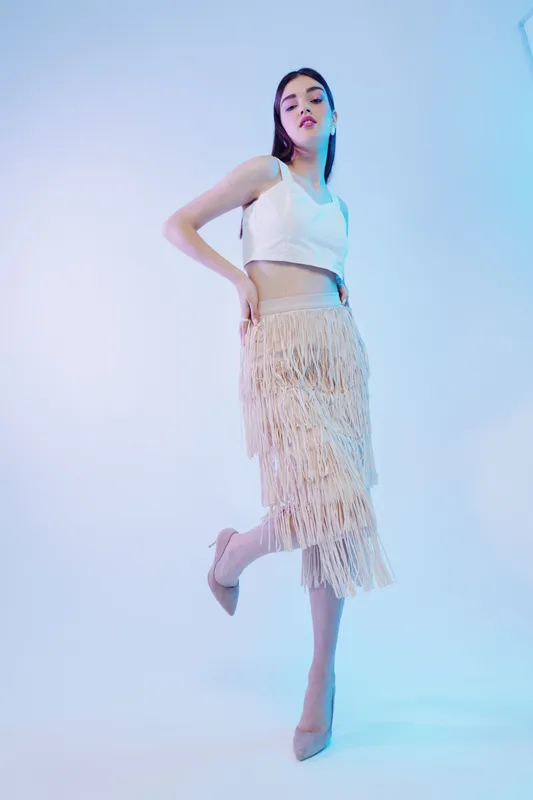 Young woman in stylish fashion outfit poses confidently in a studio with soft blue lighting. Concept of beauty, fashion, elegance, and modern style.