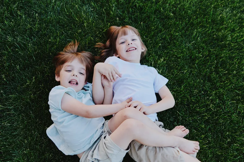 Happy children playing together on green grass, enjoying a sunny day with laughter and joy, showcasing a carefree moment of childhood happiness.