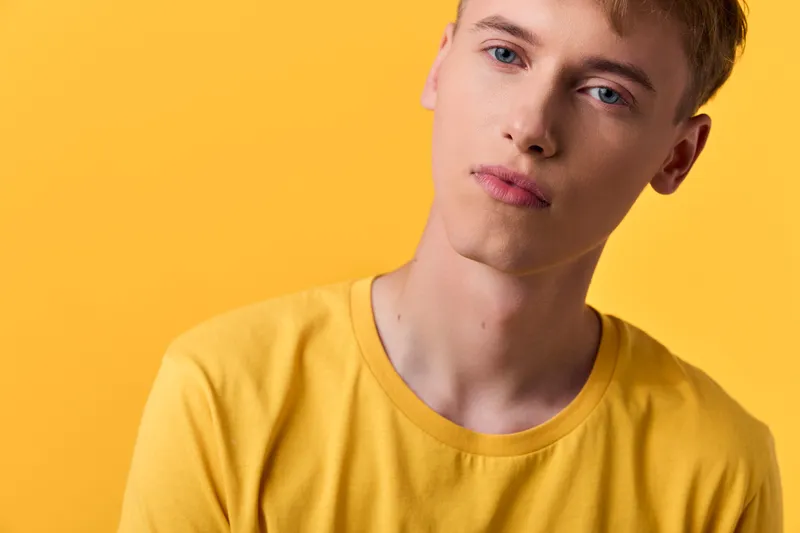 Male, young, yellow shirt in a studio closeup, highlighting facial expression and casual fashion against a vibrant backdrop, ideal for lifestyle, color harmony and modern photography