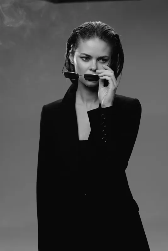 Black and white portrait of a thoughtful woman with wet hair smoking pipe against gray background.