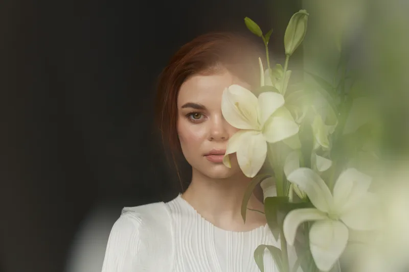 Serene young woman with flowers, conveying tranquility and beauty in a soft focused indoor setting, ideal for themes of nature and self care