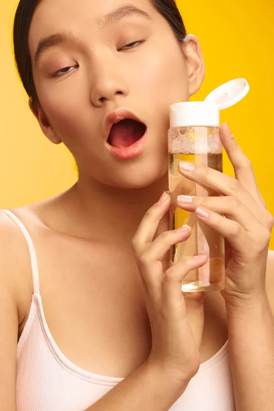 asian woman drinks water from a clear bottle in a bright setting, exuding freshness, hydration, and wellness as a simple daily ritual that promotes balance and vitality.