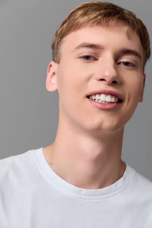 Man smiling in a white t shirt, studio setting, clean background, friendly and approachable look, ideal for lifestyle, branding and marketing campaigns