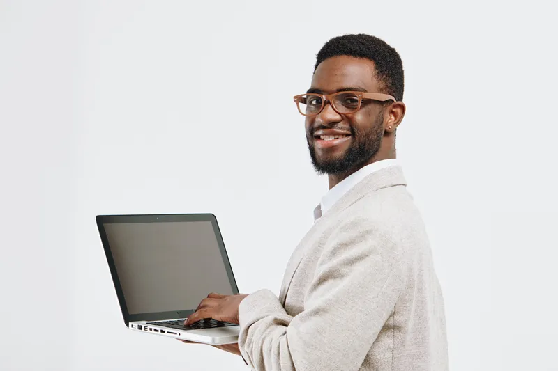 Smiling man holding open laptop in hand, wearing glasses and beige blazer, cheerful expression, professional appearance, isolated on white background, studio portrait, people lifestyle concept, positi
