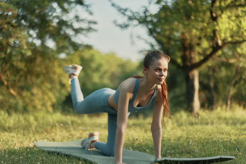 Fit young woman practicing yoga in a serene green park, showcasing a healthy lifestyle with focus and determination, perfect for wellness themes