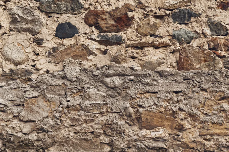 Stone wall with rough texture and natural masonry pattern creates a rustic background for architectural design and photography projects in various contexts.