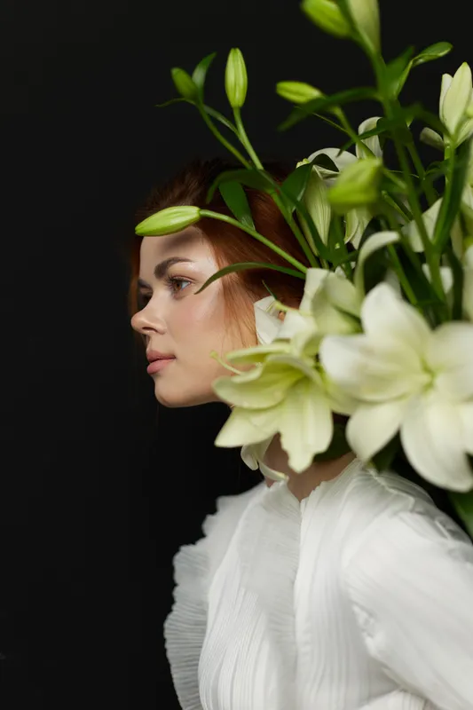 Elegant profile of a model with flowers against a black background, showcasing beauty and nature in a serene and artistic manner