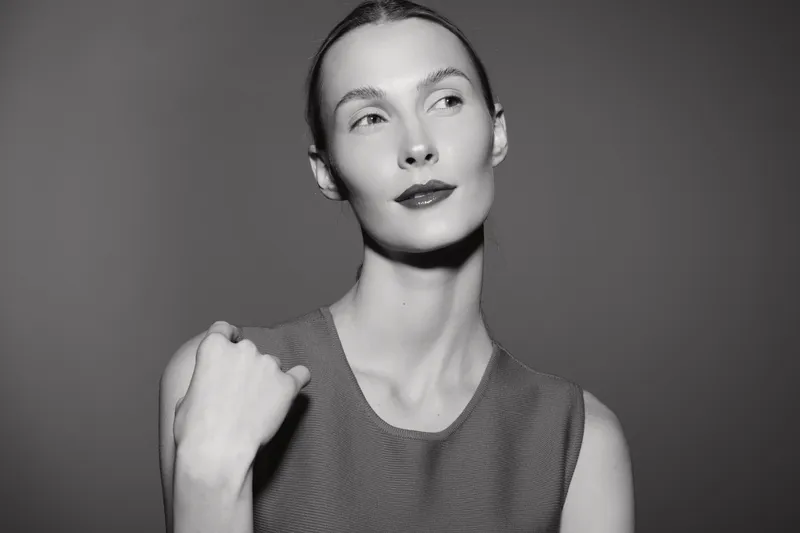 Portrait of a fair skinned Caucasian woman with slicked back hair wearing sleeveless top looking sideways in monochrome. Concept of elegance and minimalism.