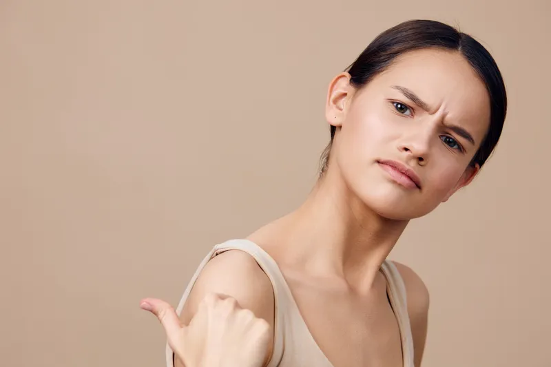 Confident young model displaying an assertive expression against a neutral background, showcasing modern fashion with a stylish look