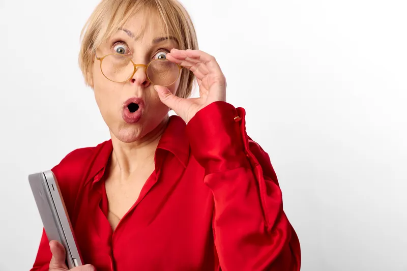 Woman surprised glasses red studio smartphone portrait, mature face touching glasses, holding smartphone, shocked expression, copy space, white background, indoors, studio lighting