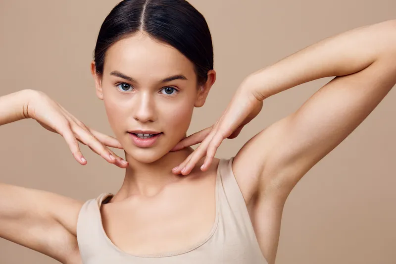 Young woman posing gracefully with a neutral background, showcasing natural beauty and confidence, perfect for beauty and skincare themes