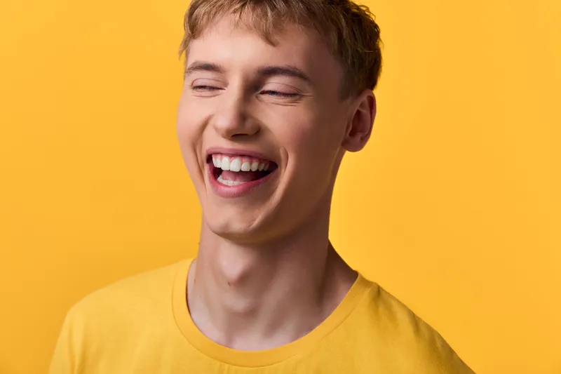 Smiling man in a yellow shirt against a bright yellow background, radiating warmth, energy, and carefree joy for lifestyle, happiness, and optimistic branding visuals.