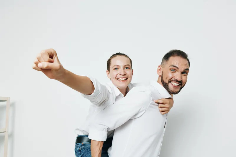 A professional businessman and colleague share a playful moment against an isolated white background, conveying confidence, teamwork, and positive emotion.