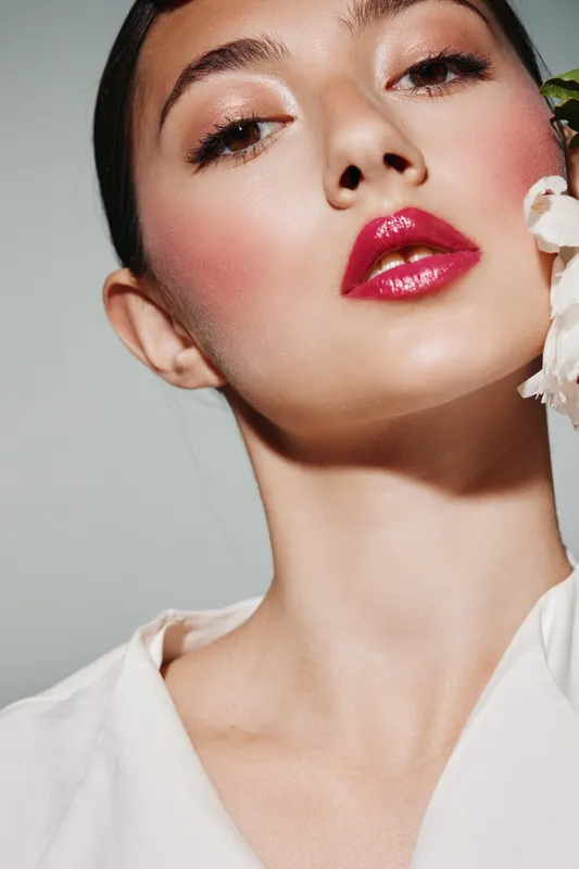 Closeup of elegant woman with bright glossy lips, soft natural makeup, and silky skin against minimal background. Concept fashion beauty creative, modern style portrait with gentle light.