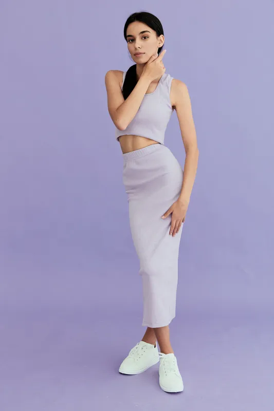 young woman posing in stylish light purple two-piece outfit with white sneakers on pastel purple background, modern fashion look, casual and chic style