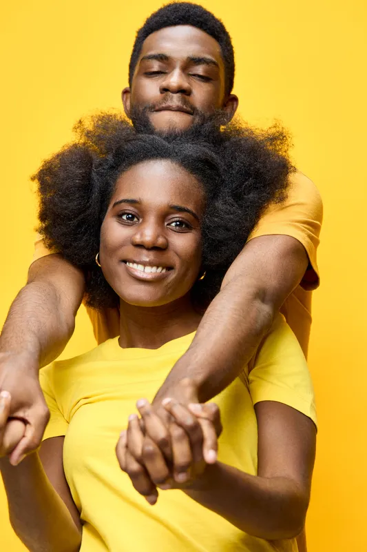 Happy African couple in yellow shirts expressing joy and love against a bright yellow background, perfect for showcasing relationships and emotions