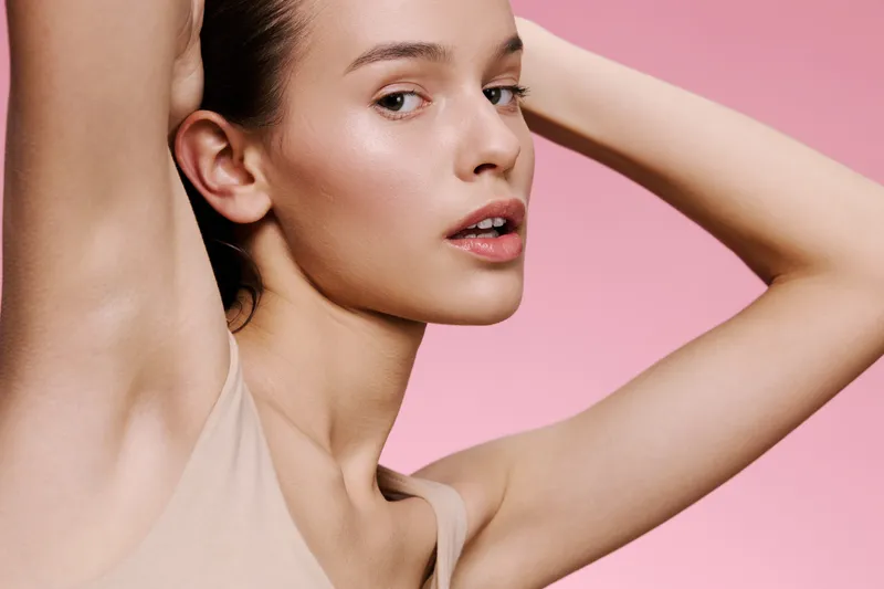 Young model with natural beauty showcasing skincare in a soft pink background, expressing confidence and serenity Concepts of beauty and self care highlighted