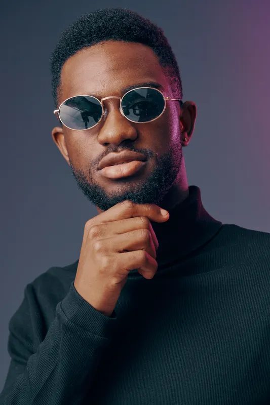 Stylish African American man in sunglasses and a black turtleneck, exuding confidence against a gradient background, perfect for fashion concepts and modern lifestyle imagery
