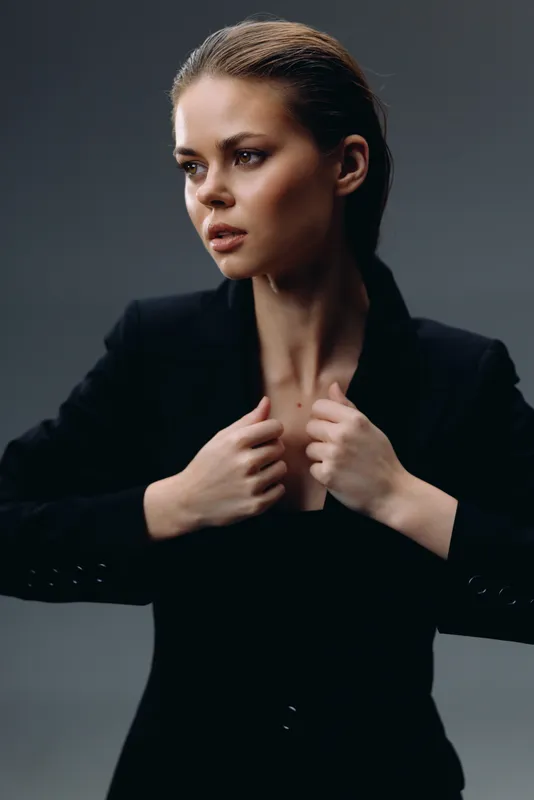 serious woman in black suit looking away with thoughtful expression and neat hairstyle