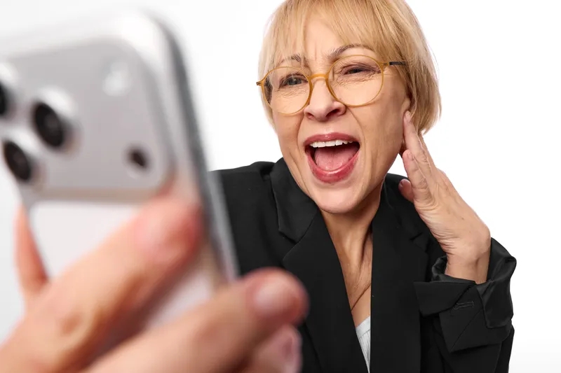 Woman portrait with smartphone calling, communication and technology, glasses, surprised expression, blurred phone in foreground, soft studio light, mobile contact and excitement