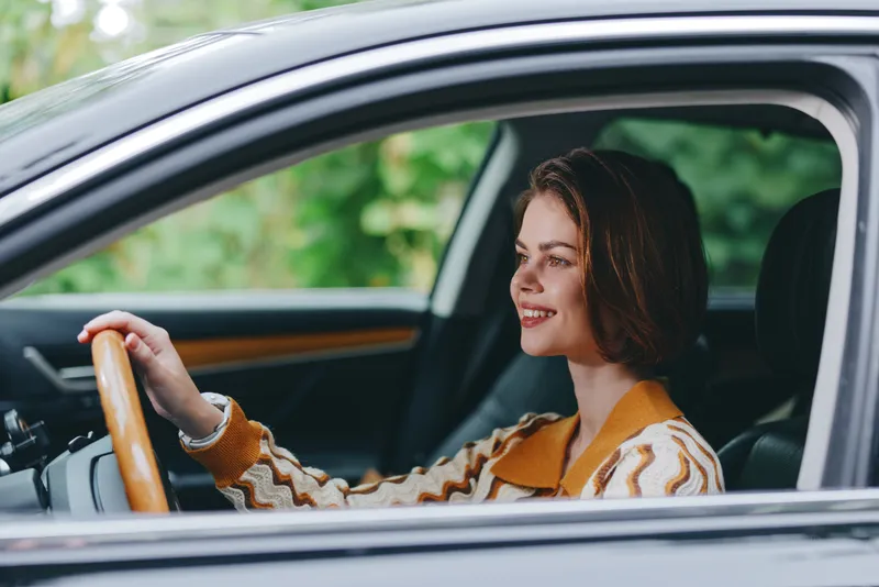 Car, driver, woman, smile a cheerful woman sits comfortably in the driver's seat with her hand confidently placed on the steering wheel, radiating joy and readiness for a journey