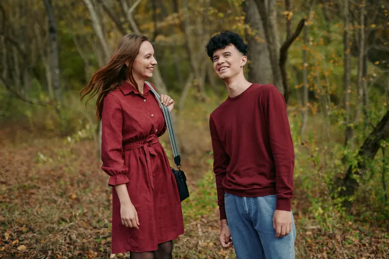 An authentic candid portrait of two individuals outdoors in autumn, capturing natural emotion, relaxed posture, and a believable moment of connection, with warm tones and soft light enhancing realism.