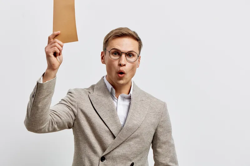 Professional man in business attire holding a blank cardboard sign, expressive face showing surprise or emphasis, isolated on plain white background, studio portrait, corporate concept, communication,